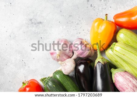 Assortment of vegetables on a light gray background. Zucchini, eggplant, sweet pepper, and garlic on the table. The concept of healthy eating. Top view with space for text