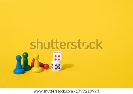 Colorful game chips and two dice are laid out on a yellow background: entertainment, games at home for the whole family, the concept of Board games. Board game. Table games