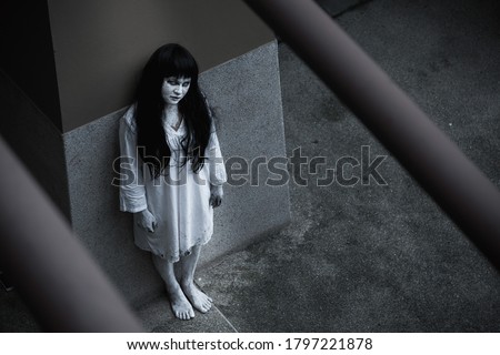 Woman ghost horror standing under building house her looking up to camera, Female in white dressed scary costume, Halloween festival day concept