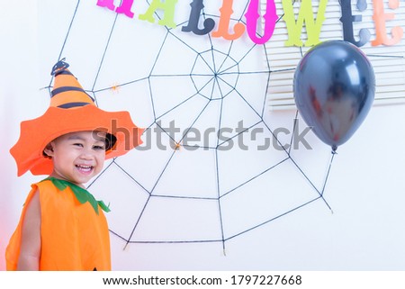 Funny happy kid in Halloween costume with pumpkin Jack and Cobweb in wall room background, Halloween festival day concept