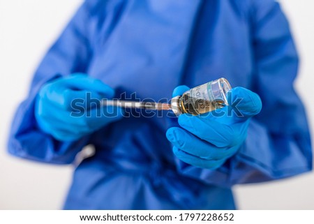 Closeup hand of woman doctor or scientist in PPE suite uniform wearing face mask protective in lab hold medicine liquid vaccine vial bottle and syringe, coronavirus or COVID-19 concept white isolated