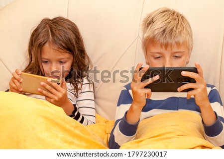 Little girl and boy playing game or watching something on mobile smart phone