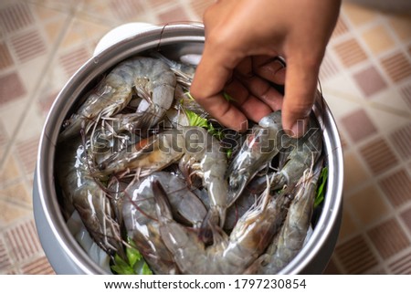 Blurred picture of people cooking shrimp or prawn and squid in pot steam in countryside kitchen. Seafood menu. Selective focus