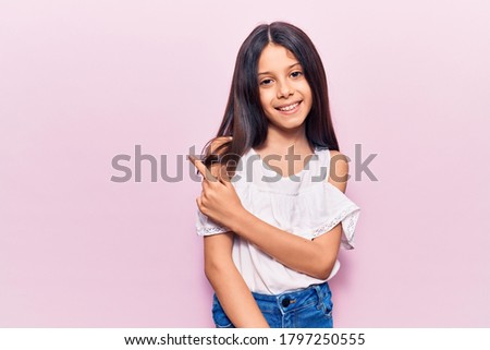 Beautiful child girl wearing casual clothes smiling cheerful pointing with hand and finger up to the side 
