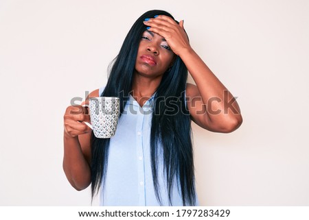 Young african american woman holding coffee stressed and frustrated with hand on head, surprised and angry face 
