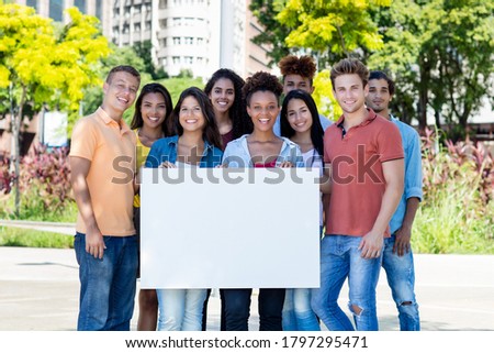 Group of friends holding blank banner outdoor in summer in city