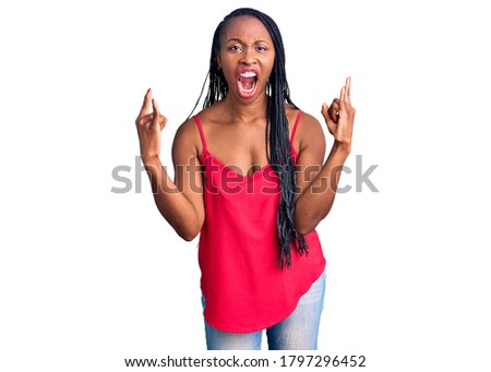 Young african american woman wearing casual clothes shouting with crazy expression doing rock symbol with hands up. music star. heavy concept. 
