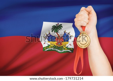 Sportsman holding gold medal with flag on background - Republic of Haiti