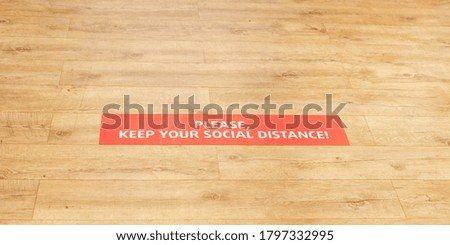 please keep your social distance words on red signboard on wooden floor of fashion store overhead view