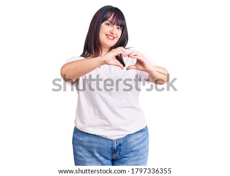 Young plus size woman wearing casual clothes smiling in love doing heart symbol shape with hands. romantic concept. 