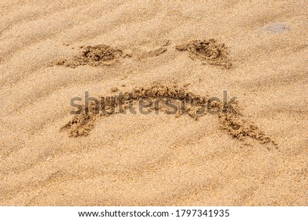 Unhappy face sign on a yellow sand. Concept state of mind