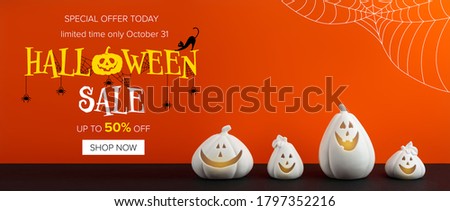 Halloween sale banner with white pumpkin shaped candle holders on bright orange background 