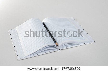 Expanded checkered notebook with open sheets and pencil. Selective focus. Blurred background.