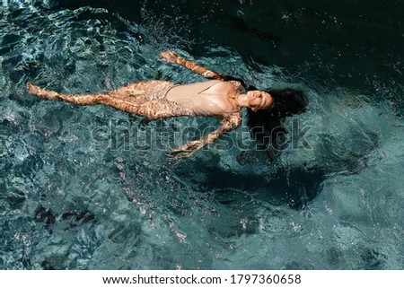 Attractive young woman floating in a swimming pool.