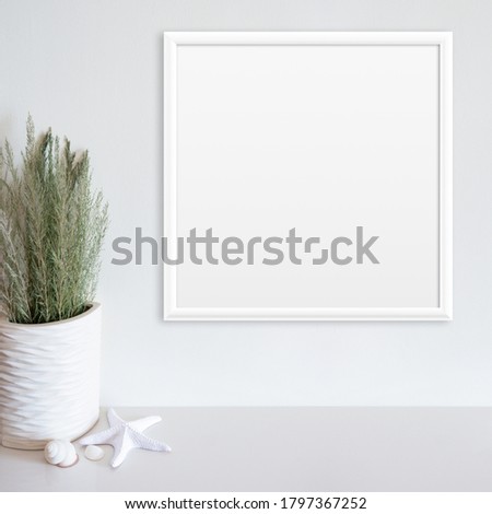 White frame mockup on white wall with beach/ocean theme decoration on white surface. Copy space.