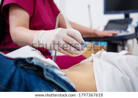A young woman lies on a couch, a doctor’s appointment, an ultrasound scan of the abdominal organs is performed on the women , the doctor examines the patient Royalty-Free Stock Photo #1797367618
