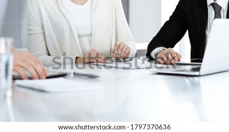 Business people discussing contract working together at meeting in modern office. Unknown businessman and woman with colleagues or lawyers at negotiation