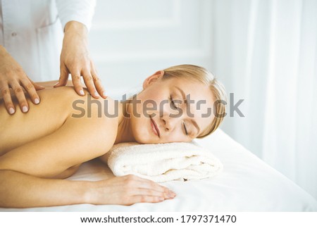 Beautiful happy woman enjoying back massage with closed eyes. Beauty and Spa salon concept
