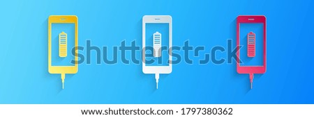 Paper cut Smartphone battery charge icon isolated on blue background. Phone with a low battery charge and with USB connection. Paper art style. Vector.