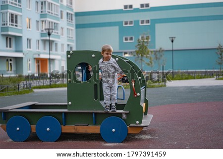 cute little caucasian boy standing on step of wooden car on playground