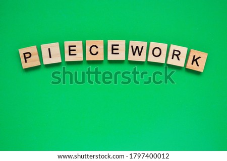 Word piecework. Top view of wooden blocks with letters on green surface Royalty-Free Stock Photo #1797400012
