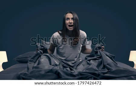 Shocked scared woman waking up from a nightmare in her bed at night Royalty-Free Stock Photo #1797426472