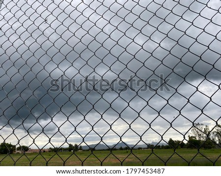 Park mountains and dark clouds beside a metal fence