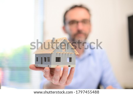 mature male architect showing a mockup sketch of architectural construction house building in architect studio workspace holding meter and keys