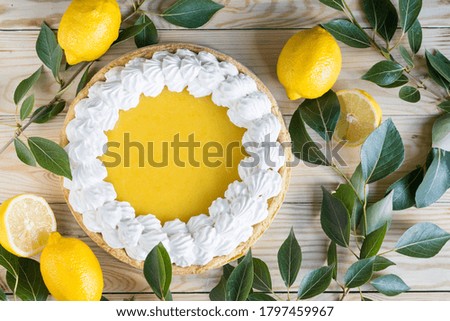Fresh homemade lemon pie with meringue on light wooden background, top view.