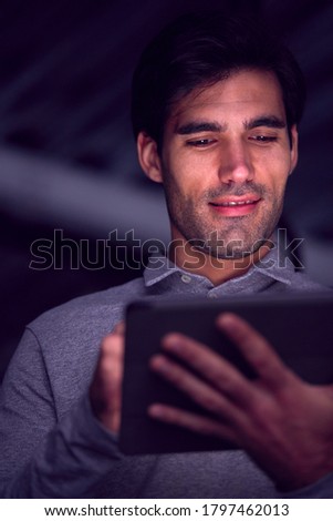 Businessman Working Late Using Digital Tablet With Face Illuminated