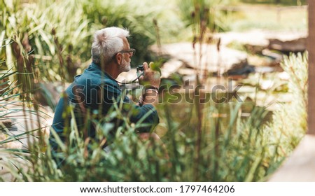 60 year old man in harmony with nature, taking pictures on the lake. Senile depression and loneliness.