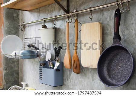 Two wooden ladles are hanging nearly black pan.Cooking and washing in the kitchen concept.Equipment ready to use for cooking food and eat.Loft wall in modern style.view of copy space.