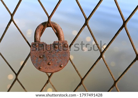 Rusty lock is locked on a metal fence