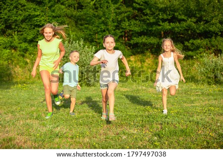 Kids, children running on meadow in sunlight, happiness
