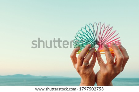 Male hands with rainbow toy spring against sea landscape. Lgbt month,  homosexual rights, gay pride parade. Space for text