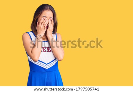 Young beautiful chinese girl wearing cheerleader uniform rubbing eyes for fatigue and headache, sleepy and tired expression. vision problem 