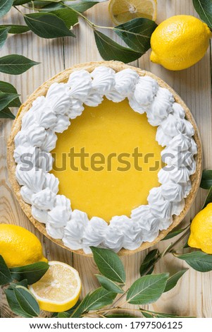 Fresh homemade lemon tart with meringue on light wooden background, top view, vertical orientation.