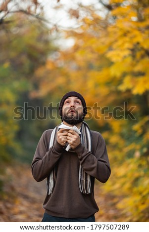 Sick man blows his nose on an autumn day