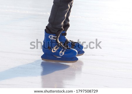 legs of a man in blue skates rides on an ice rink. hobbies and leisure. winter sports