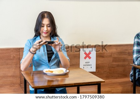 Young attractive asian teen female influencer, foodie blogger take photo of food or lunch by smartphone camera in restaurant after covid pandemic reopen feeling satisfy, happy and enjoy with food.
