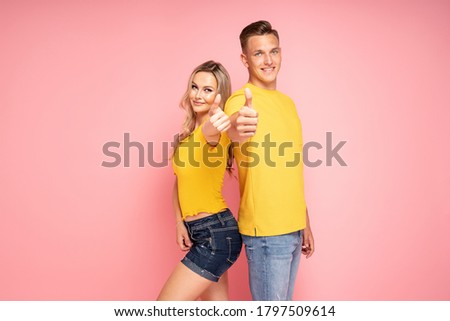 Beautiful young couple smiling, posing on pink pastel studio background.