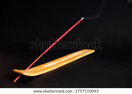 ssmoking incense stick on wooden stand on black background.