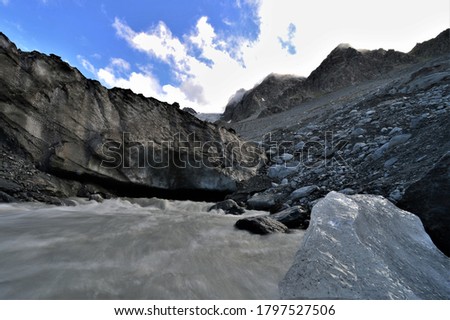 Glacier river from a glacier cave in the alps in valais in switzerland with a bright blue sky