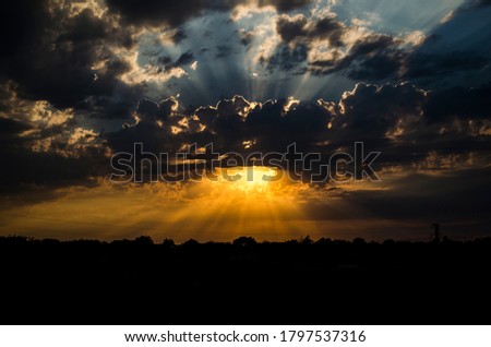 The Golden rays of the sun pass through the clouds in the evening sky. The time of sunset.