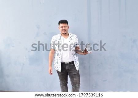 Excited traveler tourist man in white clothes isolated on blue background. Passenger traveling abroad on weekend. Air flight journey concept. Work on laptop,