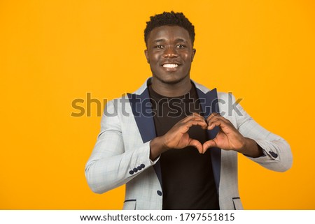 handsome young african male in a jacket, on a yellow background, with a hand gesture