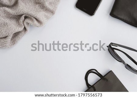 Set of fashion accessories on gray background. Sweater, handbag, smartphone, sunglasses and paper bag. Shopping, Black Friday concept. Top view, flat lay, copy space