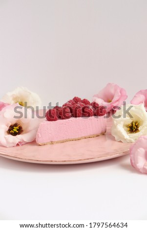 Raspberry cheesecake with fresh flowers food photo, pink cake with berries on a plate on white background concept food art