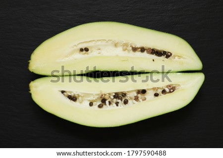 Photography of a green papaya also know as pawpaw cut in half on slate background for food illustrations