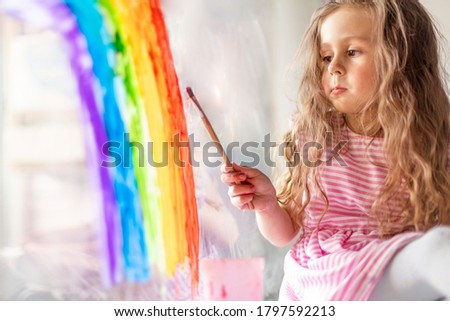 child at home draws a rainbow on the window. Flash mob society community on self-isolation quarantine pandemic coronavirus. Children create artist paints creativity vacation